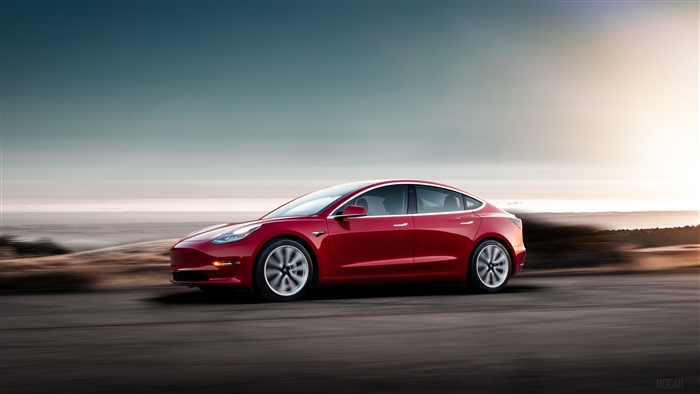 Red 2018 Tesla Model 3 driving on road