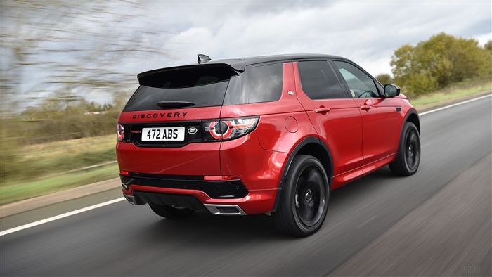 Red Land Rover Discovery Sport driving on road