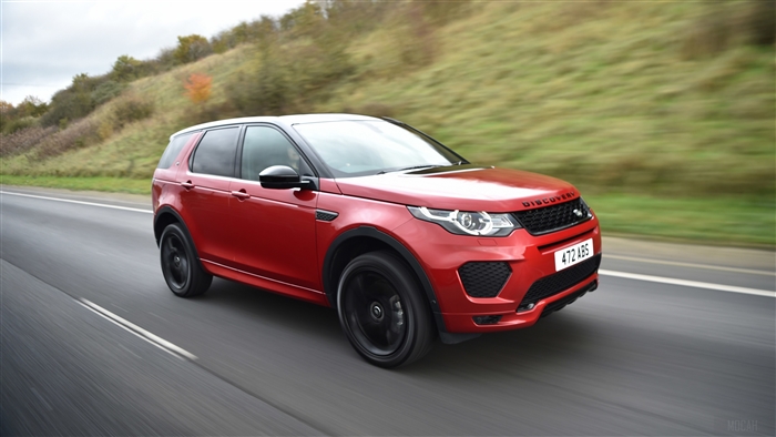 Red Land Rover Discovery Sport driving on road