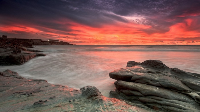 Sunset over rocky coastline with ocean waves