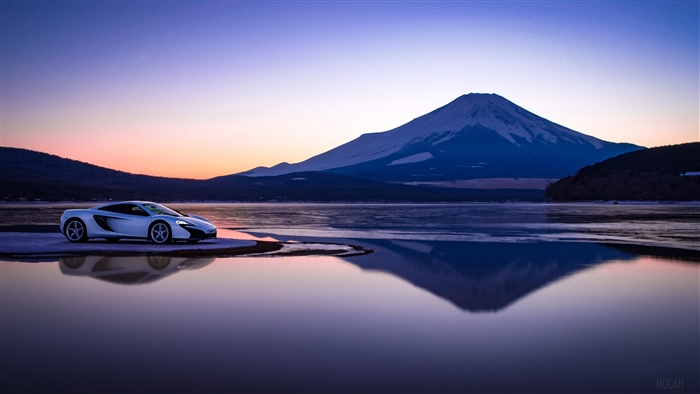 McLaren sports car by a lake with Mount Fuji at sunset