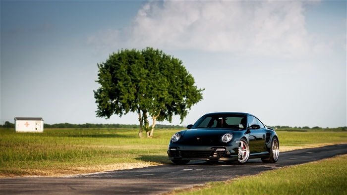 Black Porsche 911 Turbo 997 on a road with a tree