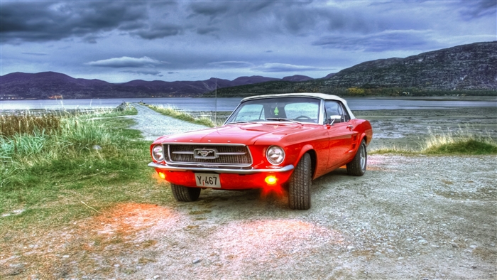 Red Ford Mustang convertible on a gravel road