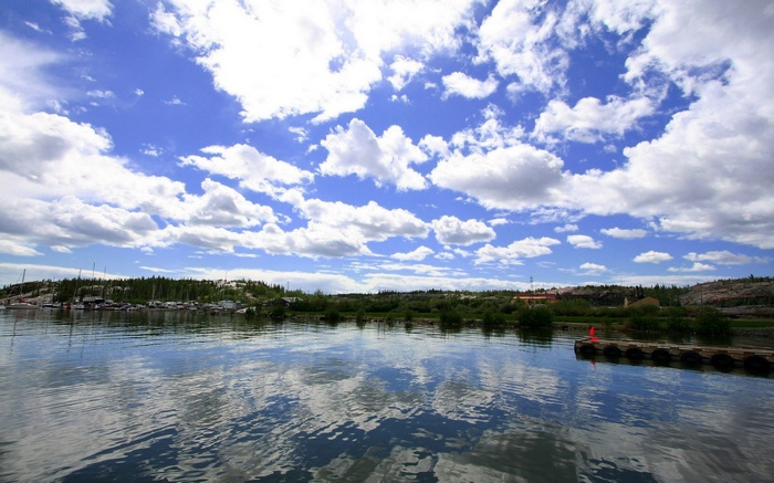 Boats docked on a lake with a cloudy blue sky