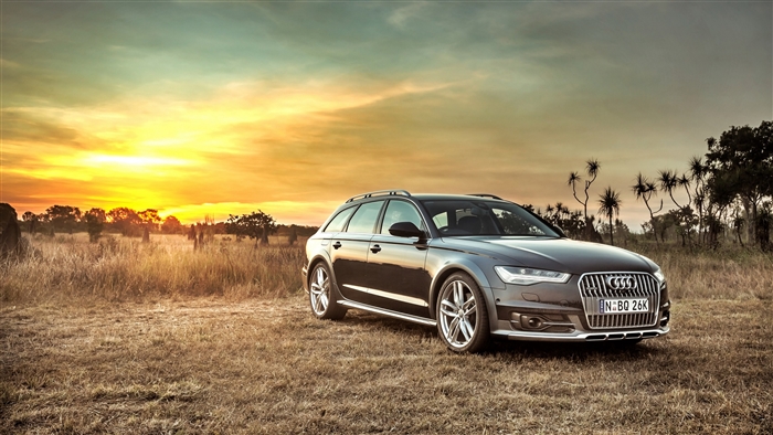 Audi A6 Allroad parked in a field at sunset