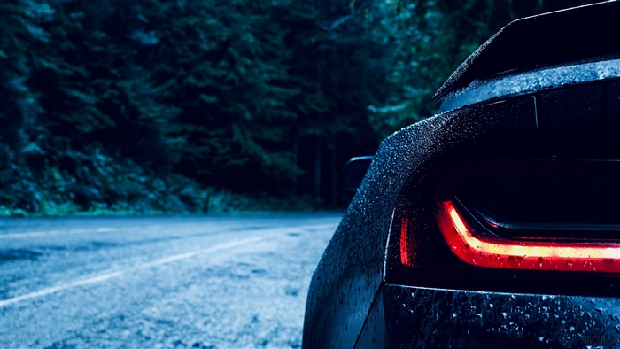 Dark car with red taillight on wet road