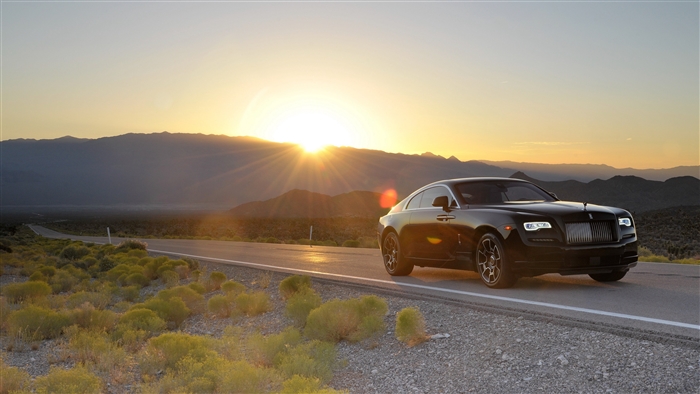 Black Rolls-Royce Wraith on a desert road at sunset