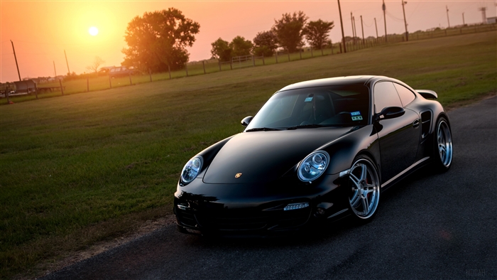 Black Porsche 911 Turbo 997 on asphalt at sunset