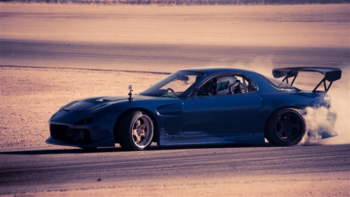 Blue Mazda RX-7 drifting on a track