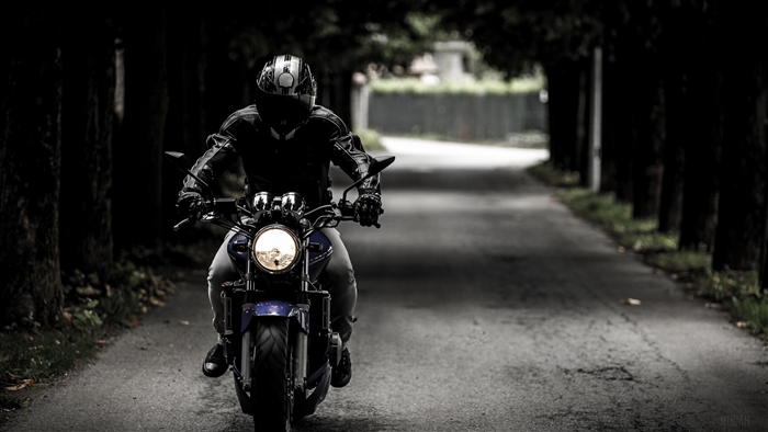 Motorcyclist wearing helmet riding motorcycle on road