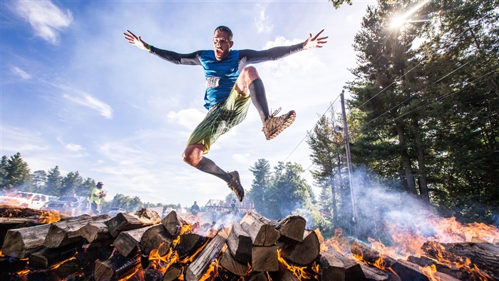 Man jumping over burning logs obstacle course 4K
