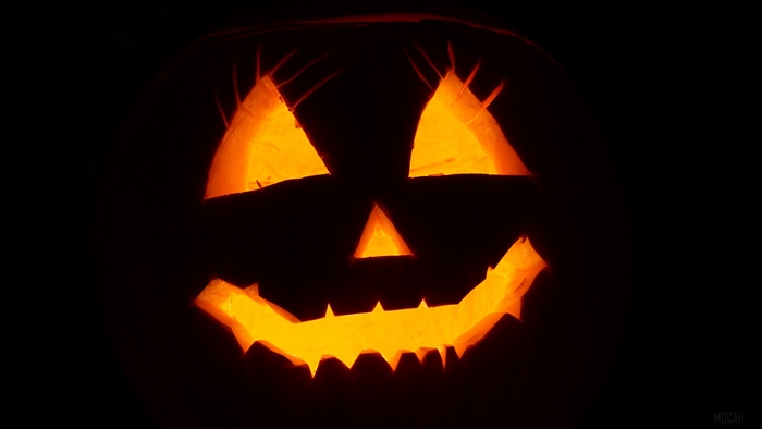 Carved Halloween pumpkin with a face on a black background 4K