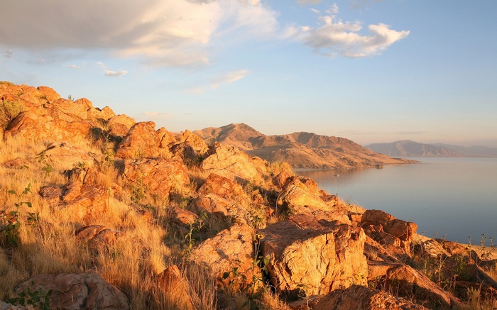 Rocky hillside overlooking a calm lake and distant mountains