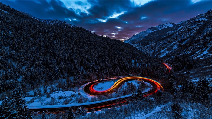 Winding mountain road with light trails in snow 4K