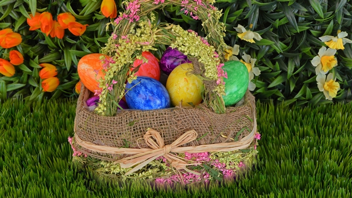 Easter basket with colorful eggs and flowers