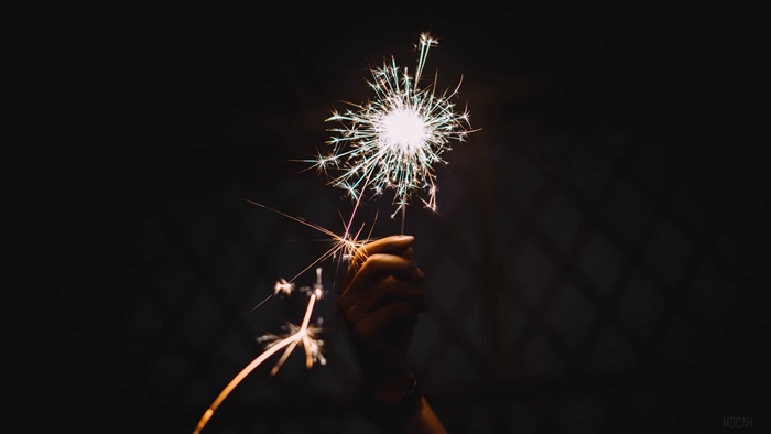 Hand holding a sparkler with sparks flying