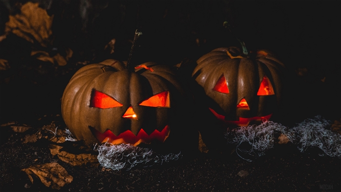 Two carved pumpkins with glowing orange faces in the dark