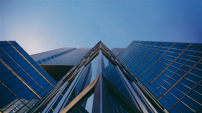 Glass building facade from below against blue sky 4K