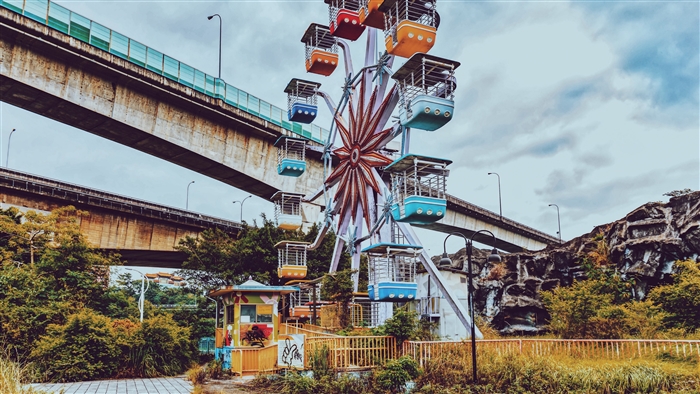 Abandoned Ferris wheel under a bridge