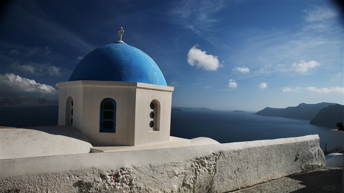 Blue dome church in Santorini, Greece with sea and mountains