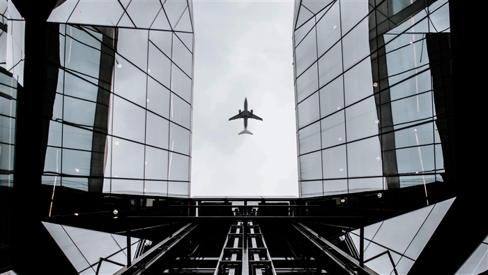 Airplane flying between modern buildings, bottom view