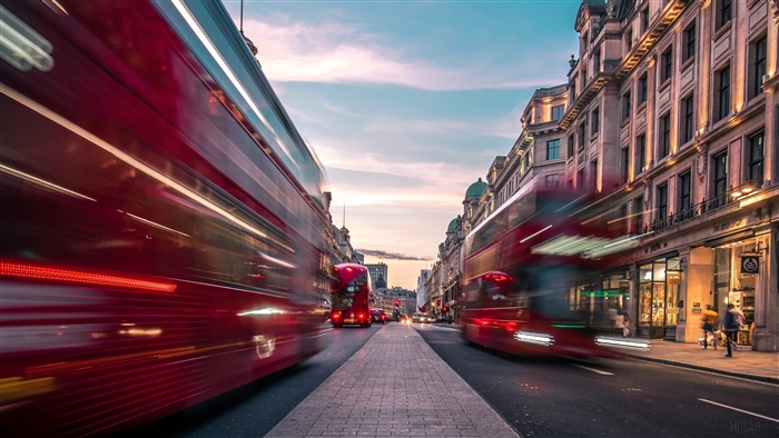 Red double-decker buses in motion on a London street