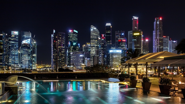 Singapore skyline at night with illuminated skyscrapers and a pool