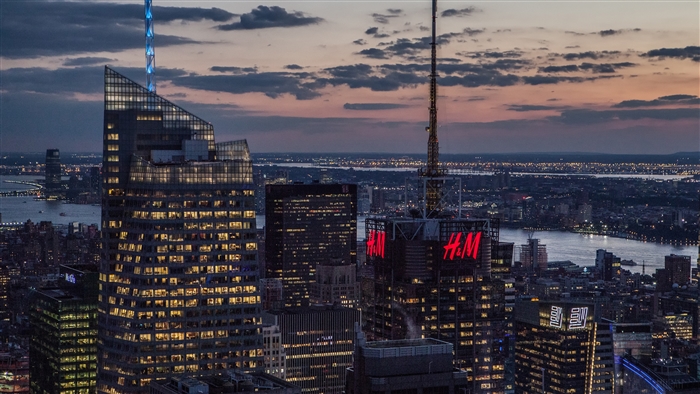 New York City skyscrapers at dusk with H&M signs