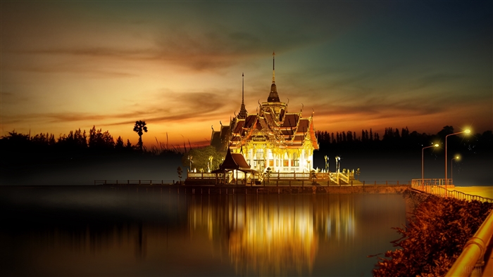 Buddhist temple illuminated at sunset with reflection in water