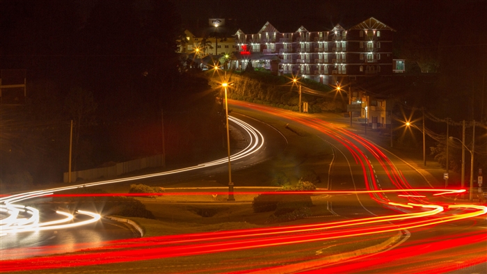 Night road with light trails and a building
