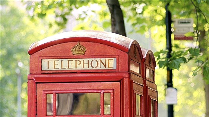Red telephone booth in London with trees