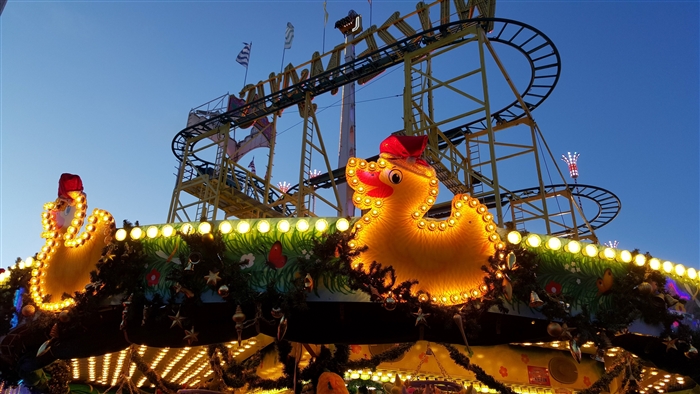 Roller coaster with illuminated duck decorations at dusk
