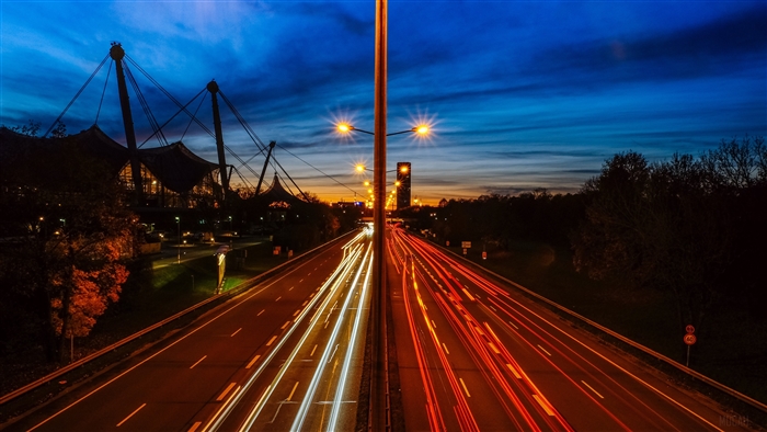 Highway at night with light trails and stadium