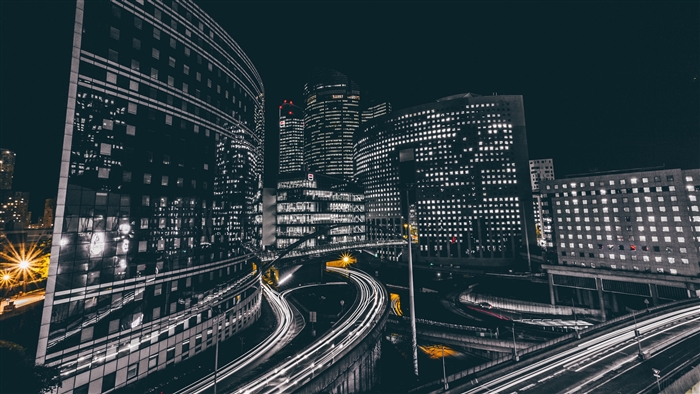Night city with illuminated buildings and light trails on roads