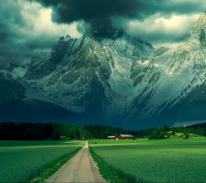 Snow-capped mountains over a green valley with farmhouses