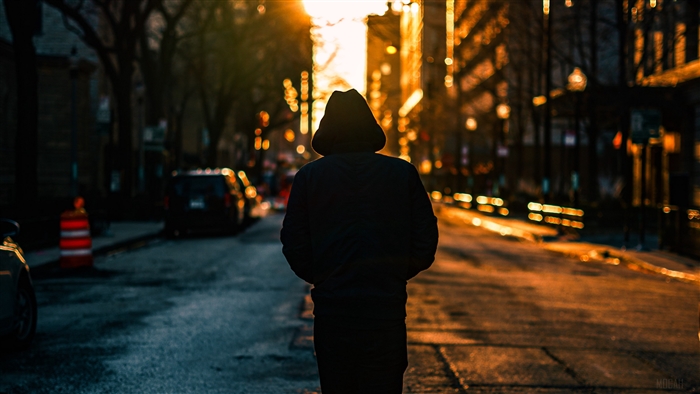 Man in Hood Walking Down City Street at Sunset 4K