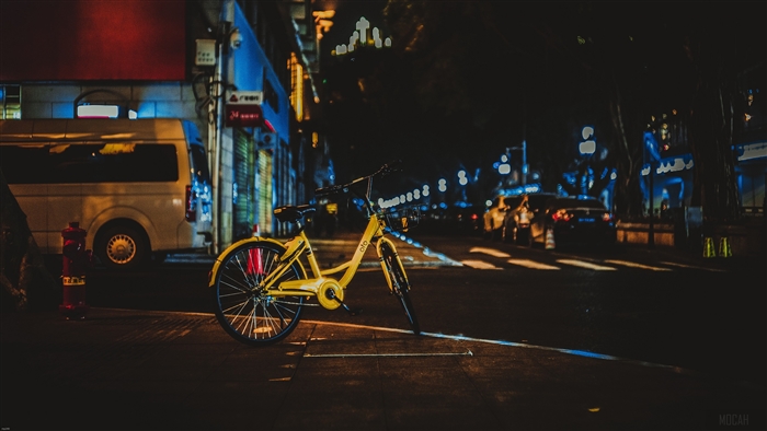 Yellow bicycle parked on a city street at night