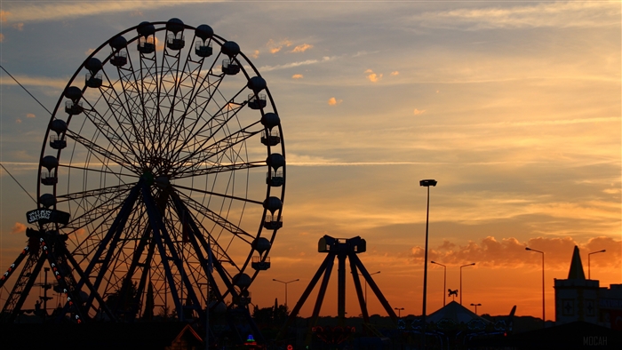 Ferris wheel and amusement park rides at sunset