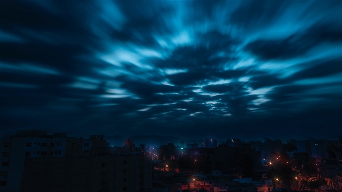 Night sky with moving clouds over a city
