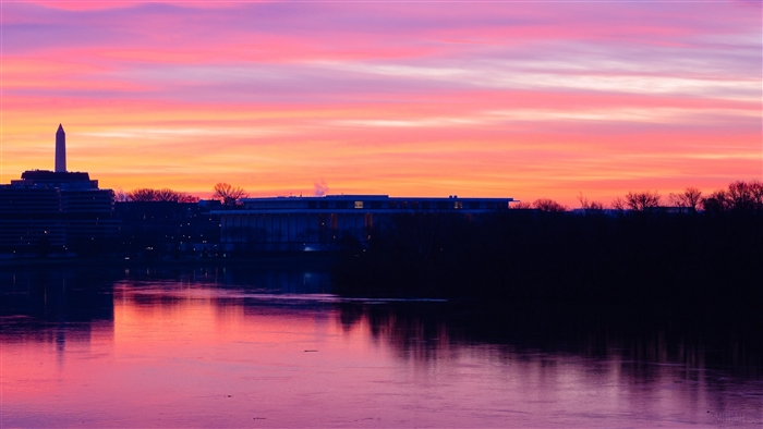 Washington Monument and buildings at sunset over river