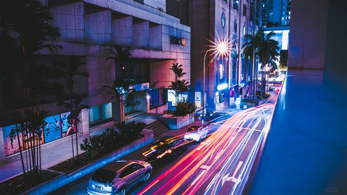 City street at night with car light trails and HSBC building