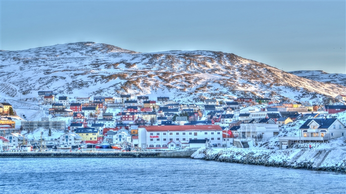 Coastal town in Norway with snow-covered hills and harbor