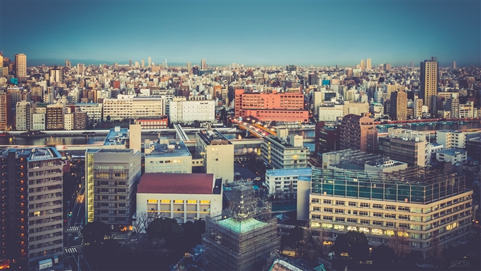 Cityscape with buildings and a river at dusk