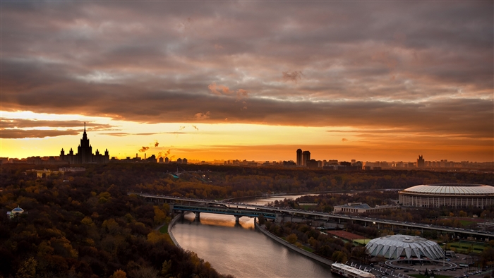 Moscow cityscape with river and stadium at sunset