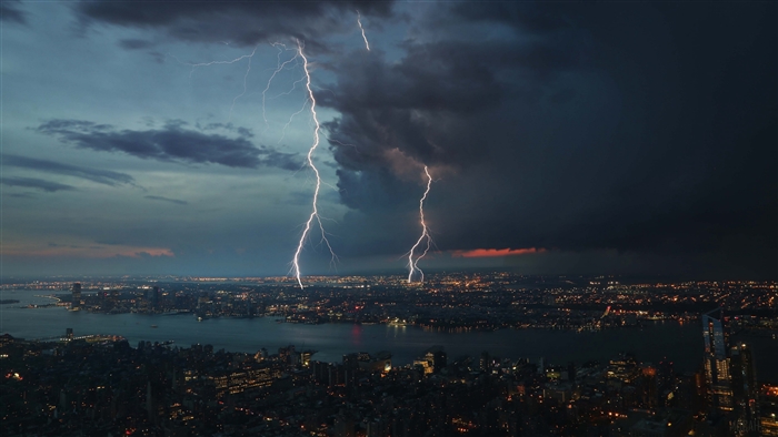 Lightning strikes over a city at dusk