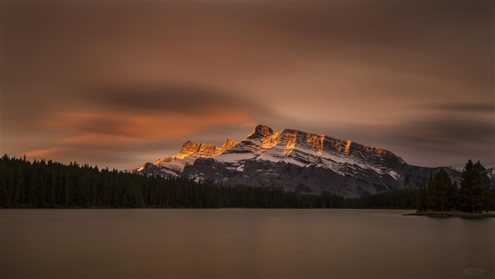 Mountaintop illuminated by sunset over a lake in Banff National Park 4K