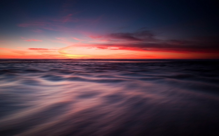 Sunset over ocean with blurred waves