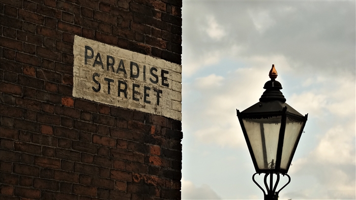 Paradise Street sign on brick wall with lamppost