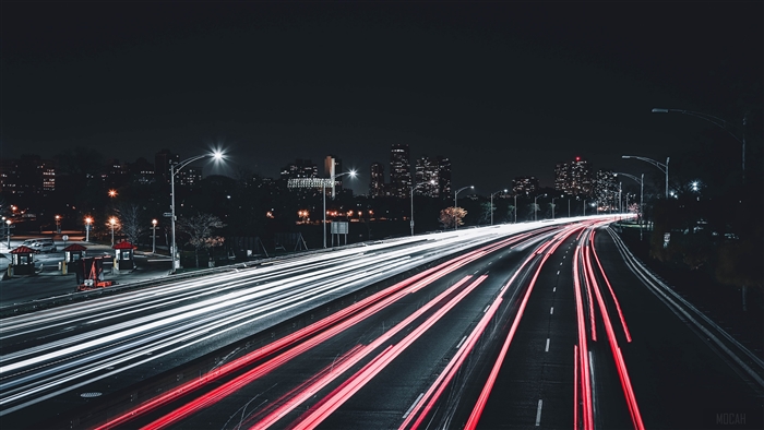 Night highway with light trails and city skyline