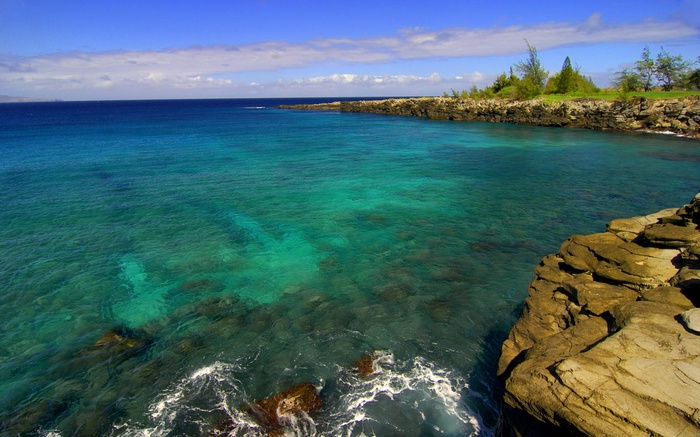 Turquoise ocean water meets rocky coastline under a blue sky